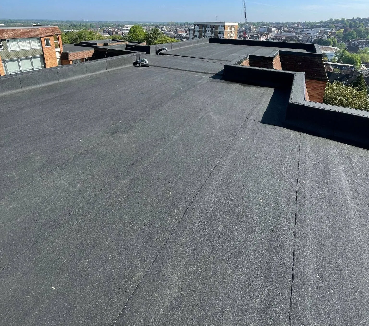 Wide view of completed felt roofing on residential flats in Guildford